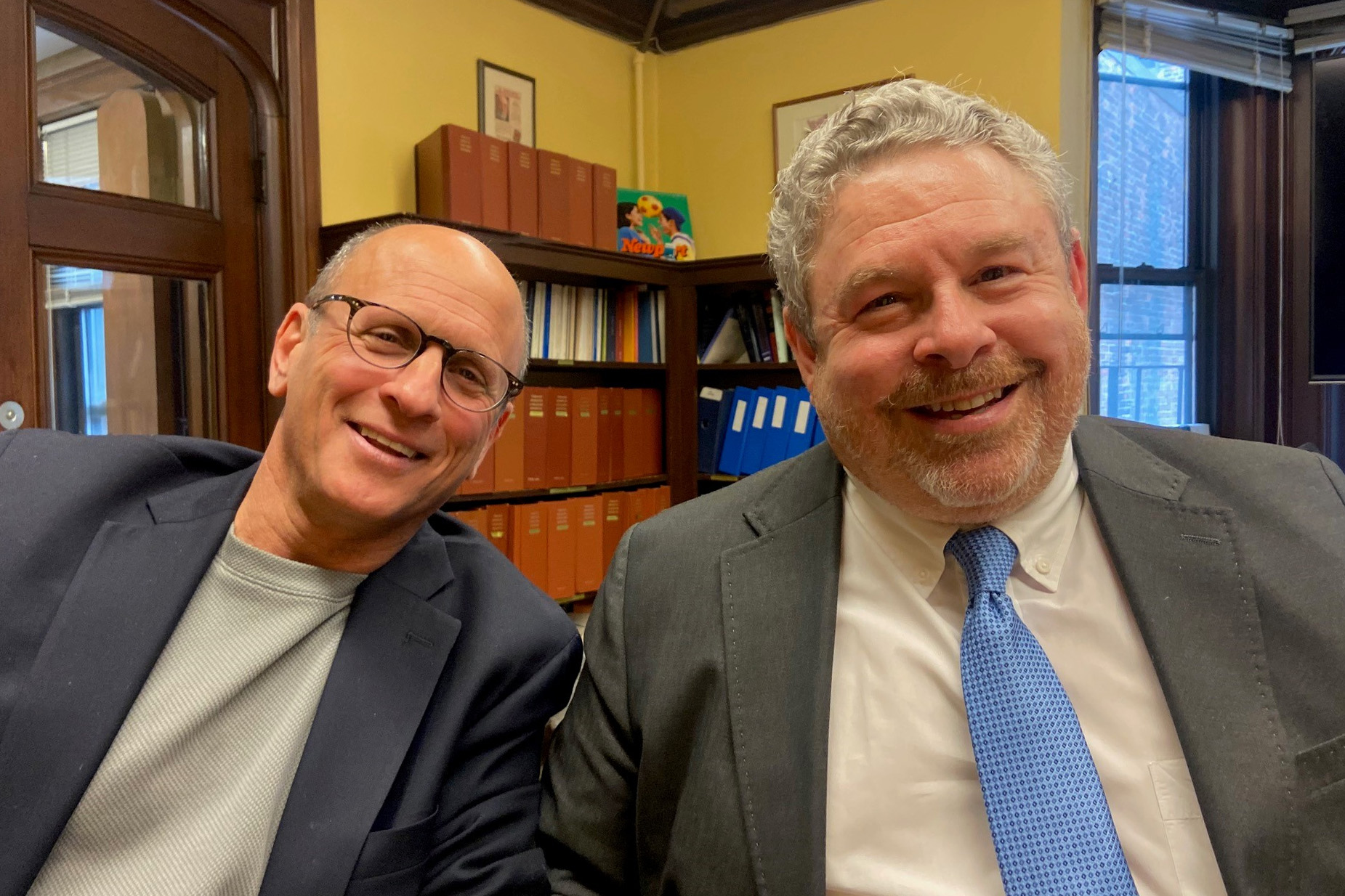 A photo of two men sitting indoors.